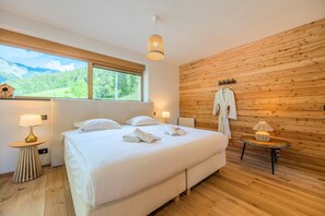 Un dormitorio moderno con una cama grande, paredes de madera y vistas a un paisaje verde.