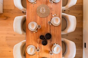 Ein Holztisch mit weißen Tellern, Tassen und einer gewebten Tischmatte.