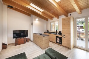 A modern kitchen with wooden cabinets, a built-in oven, and a window overlooking a balcony. - AffittiPontediLegno-Sofia&Ferdy Alpine LuxuryView (Ponte di legno)