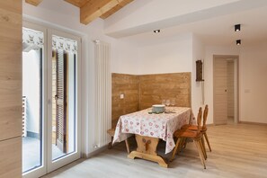 A dining area with a table set for two, wooden chairs, and a window with curtains. - AffittiPontediLegno-Sofia&Ferdy Alpine LuxuryView (Ponte di legno)