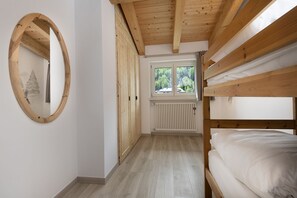 A room with a bunk bed, a wooden ceiling, a radiator, and a window with a view of trees. - AffittiPontediLegno-Sofia&Ferdy Alpine LuxuryView (Ponte di legno)