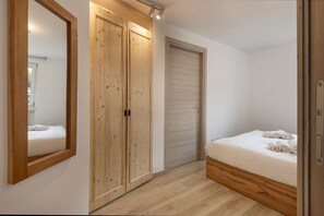 A bedroom with a wooden wardrobe, a bed with rolled towels, and a mirror on the wall. - AffittiPontediLegno-Sofia&Ferdy Alpine LuxuryView (Ponte di legno)