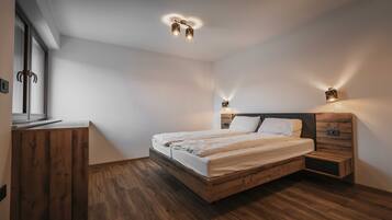 Un dormitorio moderno con una cama de madera, mesitas de noche y un armario.