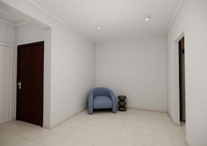 Una habitación con puerta de madera, una silla azul y una pequeña mesa con un objeto oscuro encima.