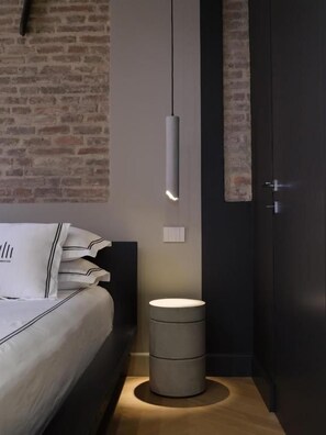 Un dormitorio con cama, mesita de noche y lámpara colgante.