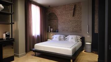 A modern bedroom with a brick wall, a bed with white bedding, a bedside table, and a hanging light fixture.