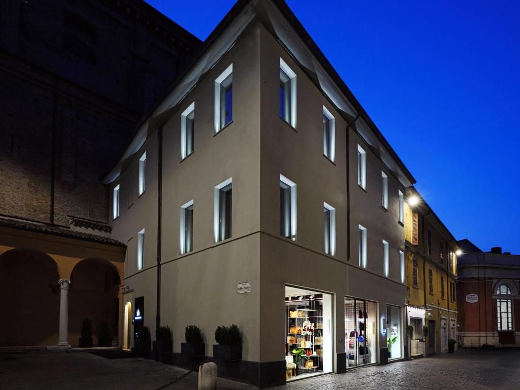 Un bâtiment doté de nombreuses fenêtres, une devanture de magasin où la marchandise est exposée, et une rue pavée.