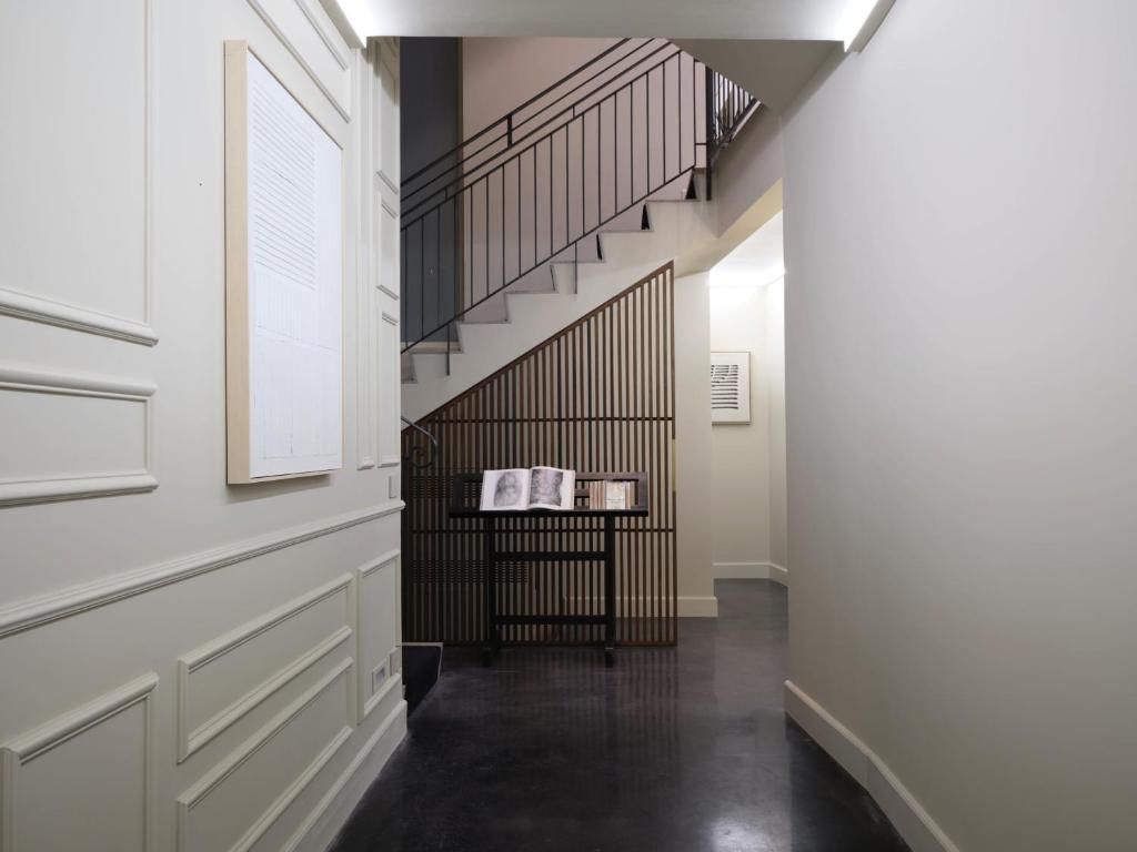 Un pasillo con una escalera, una estantería y una puerta con ventanal.
