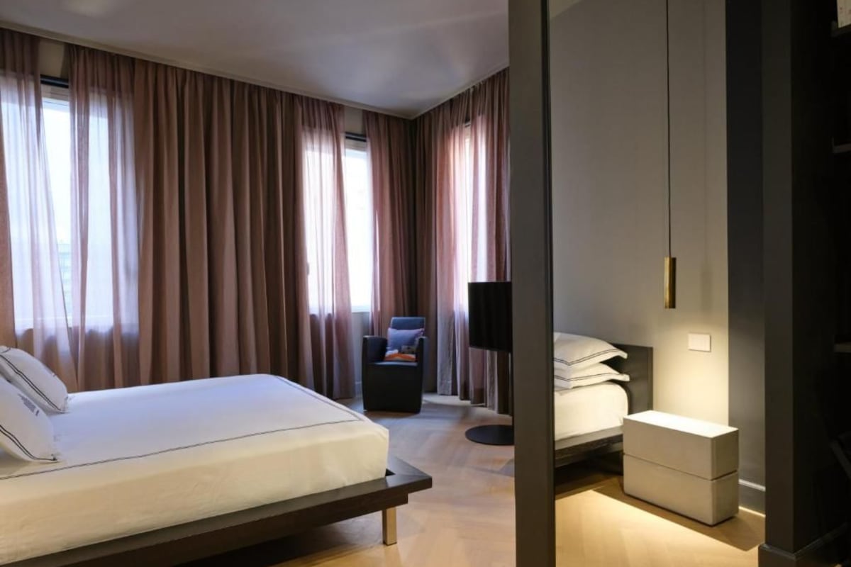 Una habitación de hotel moderna con cama, mesita de noche y una silla.