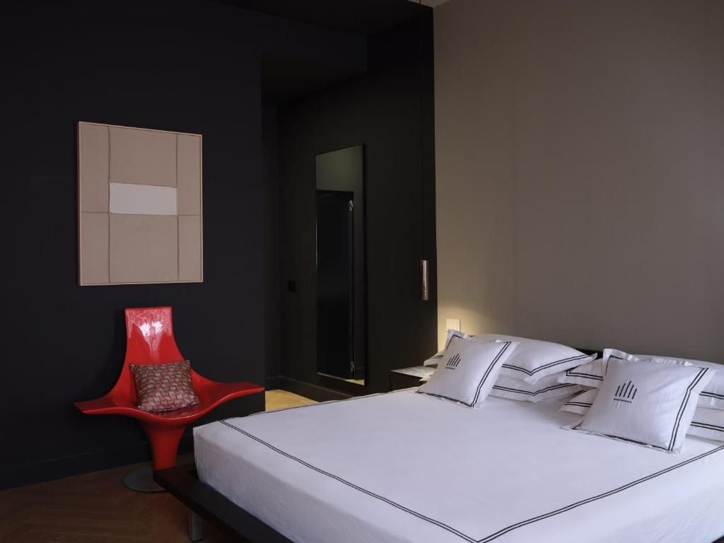 Una habitación de hotel moderna con una cama grande, una silla roja y un espejo.