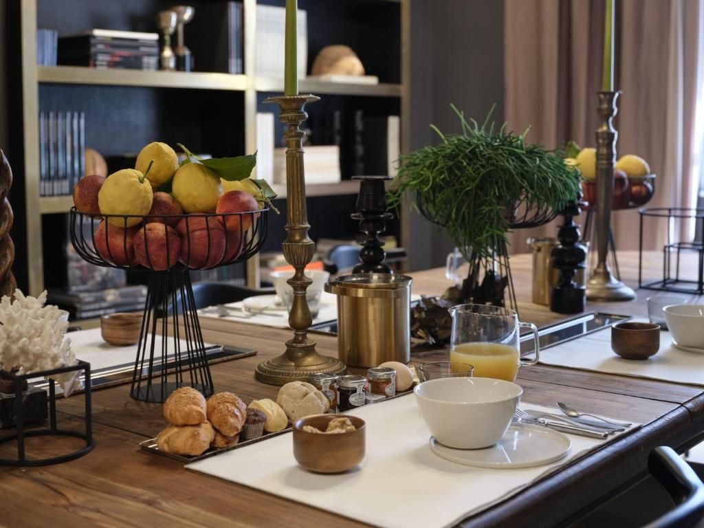 A breakfast setting with a fruit bowl, pastries, and a coffee pot on a wooden table.