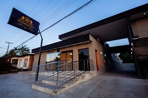 A modern building with a staircase leading to a door, a flag with a crest, and a clear sky.