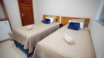 Une chambre d’hôtel avec deux lits, chacun doté d’une tête de lit, d’une petite table de chevet et d’une prise de courant fixée au mur.