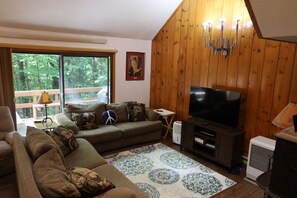 Ein Wohnzimmer mit einer Couch, einem Fernseher, einem gemusterten Teppich und einer Holzwand.