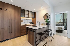 Una cocina moderna con una isla central, taburetes de bar y vistas de la ciudad a través de amplios ventanales.