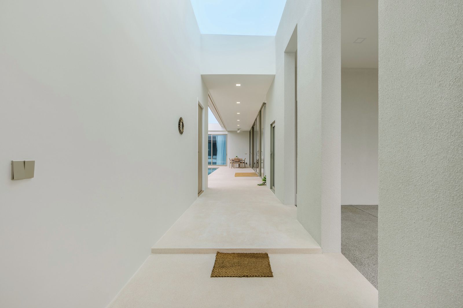 A modern interior with a straight hallway leading to a dining area.