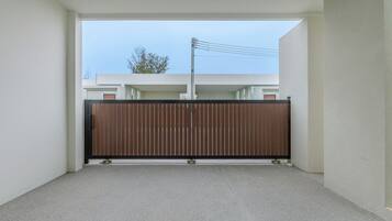 A narrow corridor with a wooden gate leading to a building with a visible power line.