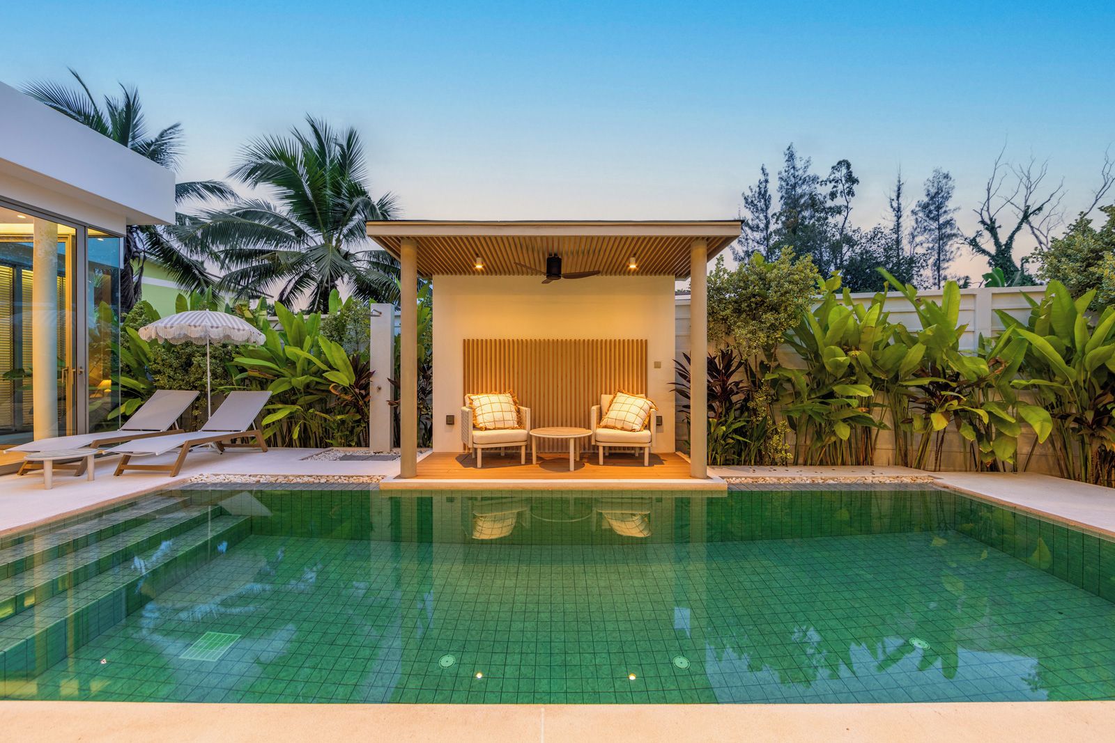 A modern outdoor pool area with lounge chairs and a covered seating area.