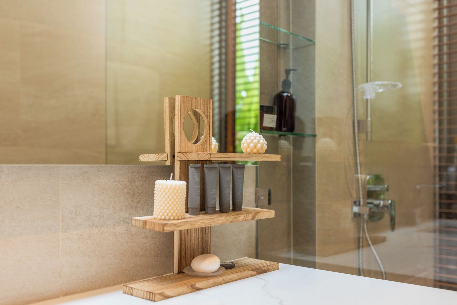 A bathroom with a wooden shelf holding toiletries, a candle, and a soap dish.