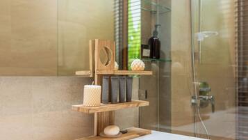 A bathroom with a wooden shelf holding toiletries, a candle, and a soap dish.