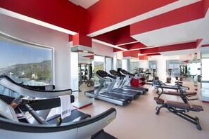 Une salle de sport équipée de tapis de course, de vélos d’exercice et d’appareils de musculation.