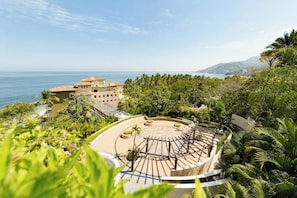 A resort with a circular outdoor area, a pool, and a view of the sea.