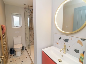 A bathroom with a toilet, a shower, a sink with a gold faucet, and a mirror with a gold frame. - The Willows (Mablethorpe)