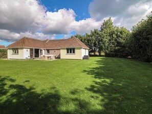 A two-story house with a covered patio and a lawn. - The Willows (Mablethorpe)