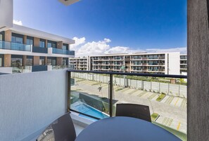 Varanda com vista para um complexo moderno de edifícios, uma piscina e uma área de estacionamento.
