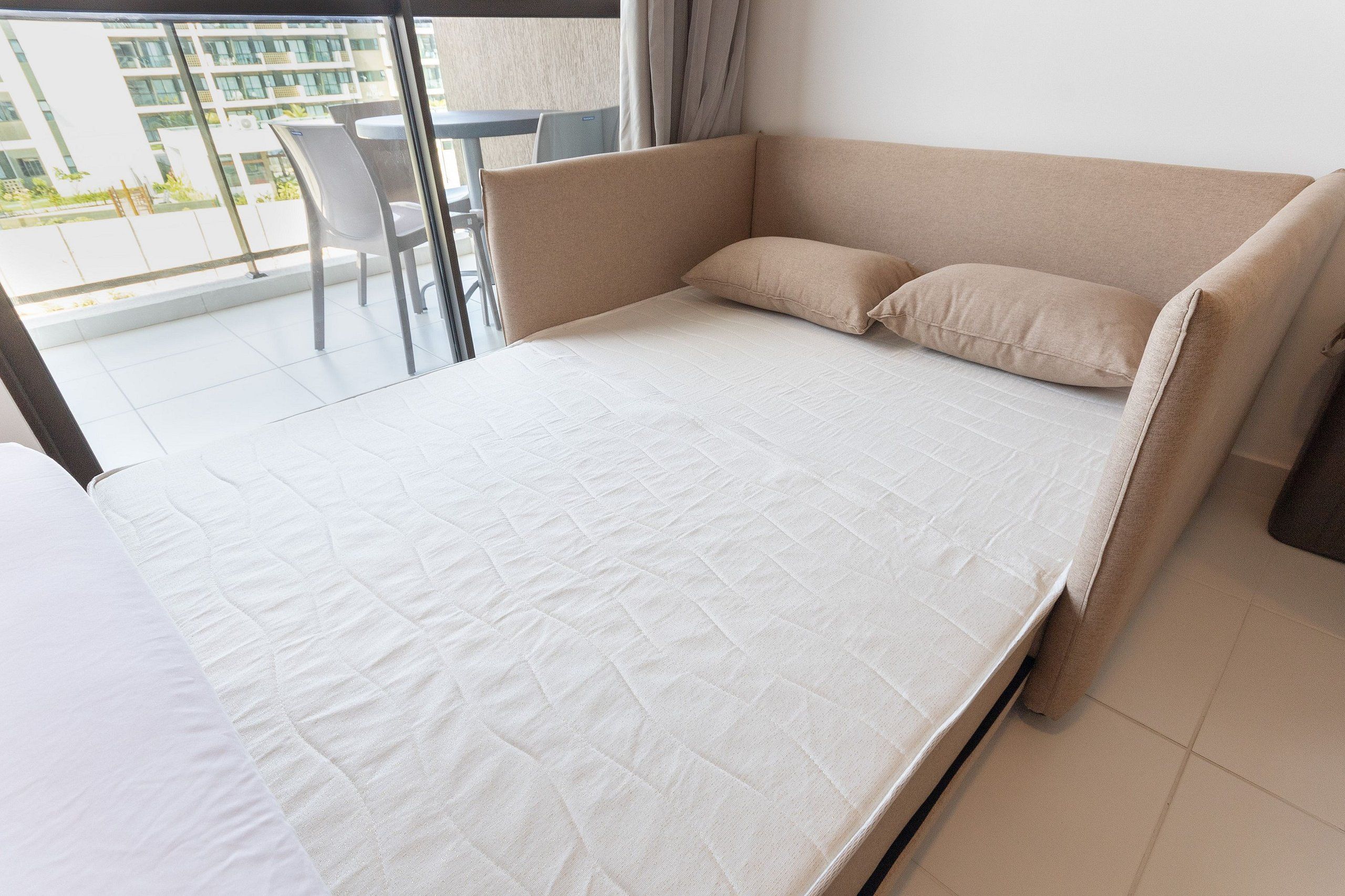 A modern hotel room with a bed, a chair, and a view of the outside.