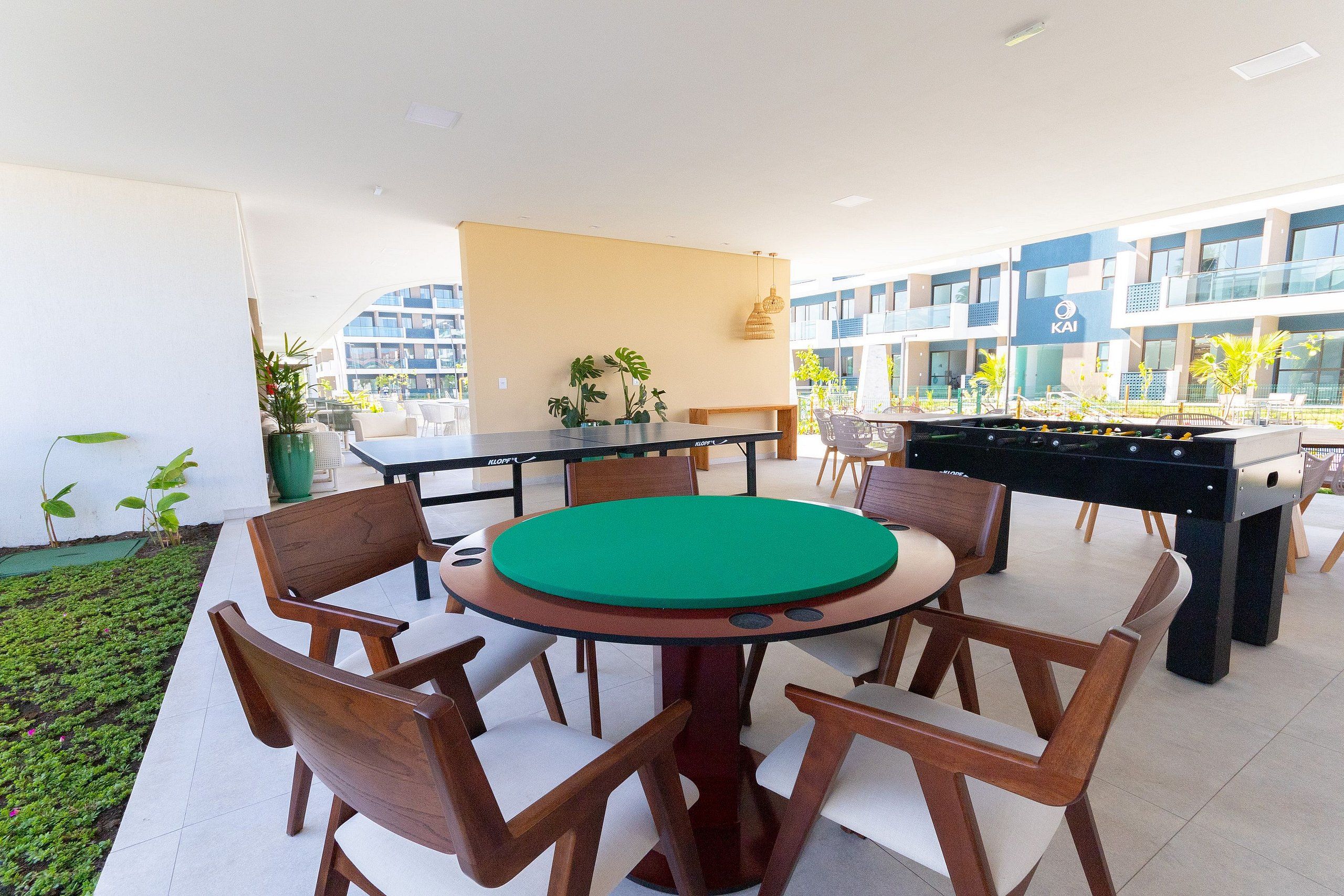 An outdoor dining area with a pool table, chairs, and a foosball table.