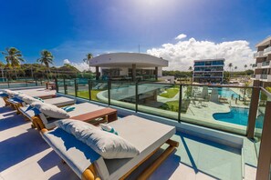 Área de piscina no terraço com espreguiçadeiras e vista para a piscina e edifícios ao redor.