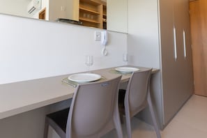 Een hotelkamer met een eettafel, twee stoelen, een telefoon en een minibar.