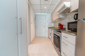 A compact kitchen with a washing machine, a microwave, and a coffee maker. - HAVN - Cozy Studio in Ghozlan, The Greens (Dubai)
