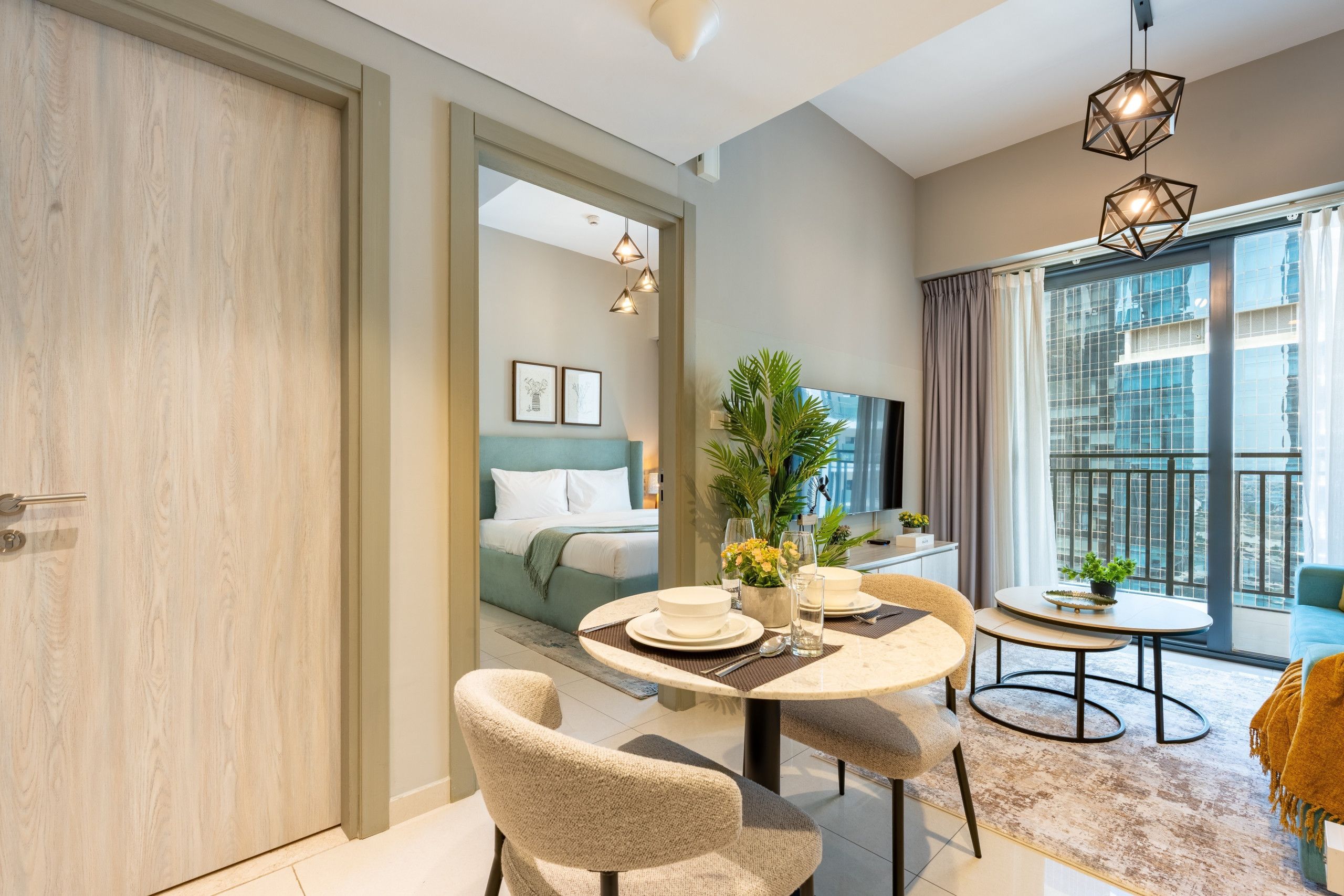 A modern hotel room with a dining area, a bed, and a large window with curtains.