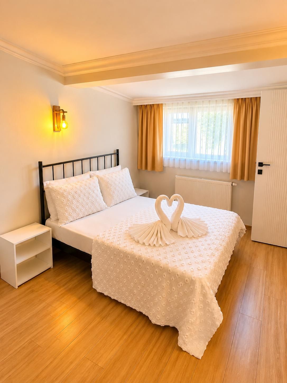 Un dormitorio ordenado con cama, mesita de noche y aplique de pared.