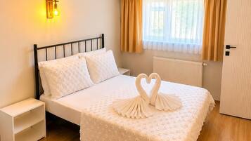 Un dormitorio ordenado con cama, mesita de noche y aplique de pared.