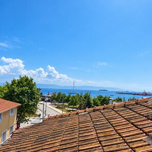 A coastal view with terracotta tiled roofs, a clear blue sky, and a distant view of the sea and ships. - Blue Sea Hotel (Tuzla)