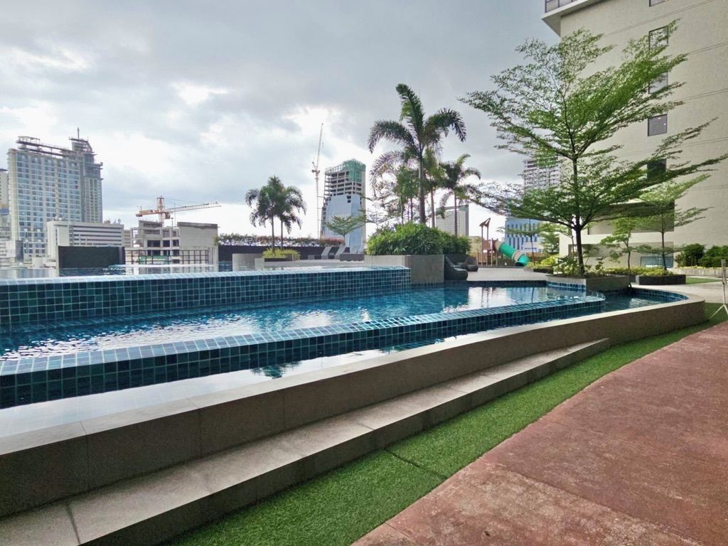 Ein Swimmingpool mit einer Fliesenverkleidung, umgeben von einer Betonplattform und einer Fläche mit künstlichem Rasen.