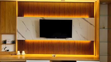 A modern entertainment unit with a flat-screen TV, wooden paneling, and marble accents.
