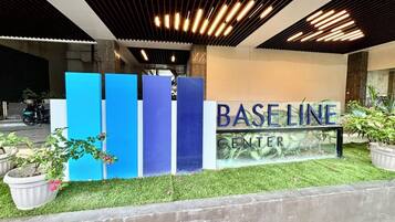 Ein Gebäudeeingang mit einem Schild, auf dem 'BASELINE CENTER' steht, und einer Reihe blauer, vertikaler Strukturen.
