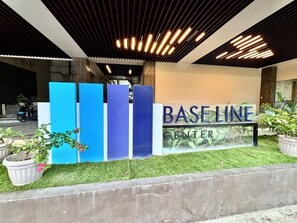 Ein Gebäudeeingang mit einem Schild, auf dem 'BASELINE CENTER' steht, und einer Reihe blauer, vertikaler Strukturen.
