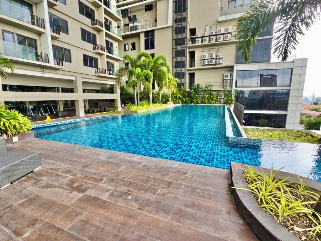 Piscina rodeada por um edifício residencial com várias andares, varandas e aparelhos de ar condicionado.