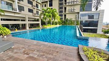 Piscina rodeada por um edifício residencial com várias andares, varandas e aparelhos de ar condicionado.