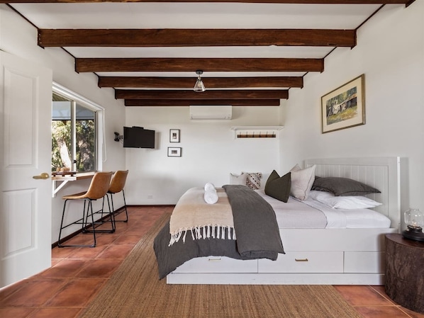 A bedroom with a bed, a desk, chairs, a window, and a picture on the wall. - Cottage at Dunmore Homestead | Peaceful Retreat (Scott River East)
