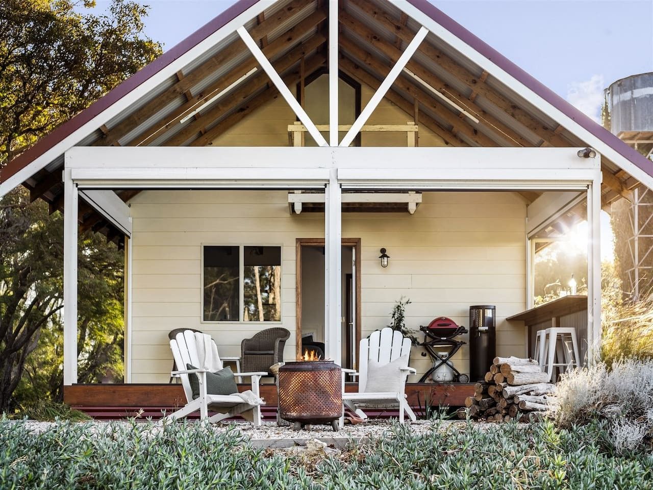 A house with a covered porch, outdoor seating, a fire pit, and a grill.