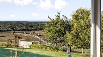 Ein Essbereich mit Blick auf eine ländliche Landschaft, ein Tisch mit Speisen und Getränken und ein Fenster mit Aussicht auf die Szenerie.