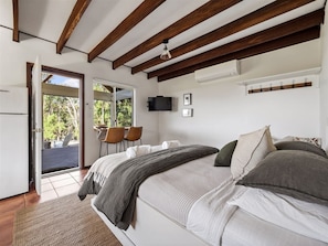 A bedroom with a bed, a desk, and a chair. There is a window and a door leading outside. - Cottage at Dunmore Homestead | Peaceful Retreat (Scott River East)