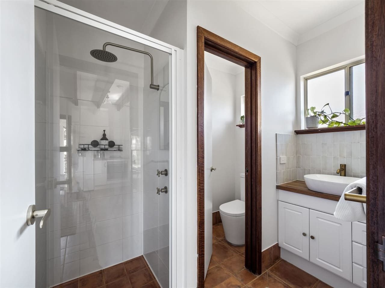 Ein modernes Badezimmer mit einer Duschkabine, einer weißen Toilette und einem Holzbadezimmerzimmermöbel mit Waschbecken.