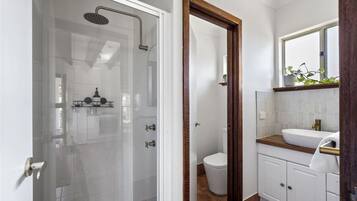 Ein modernes Badezimmer mit einer Duschkabine, einer weißen Toilette und einem Holzbadezimmerzimmermöbel mit Waschbecken.